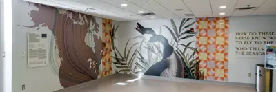A view of an interior space at YGK Airport showing the 'Homecoming' art mural which features a goose, text and other elements.
