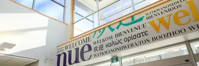 A shot of a mural featuring the word 'Welcome' written in multiple languages, positioned above a glass entrance door.