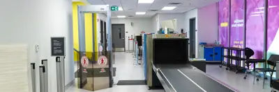 A close-up of the security area at YGK Airport, showing a metal detector and a baggage conveyor belt.